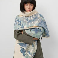 Woman wearing a luxurious soft blue and cream reversible wrap, showcasing elegant floral patterns and stylish layering.