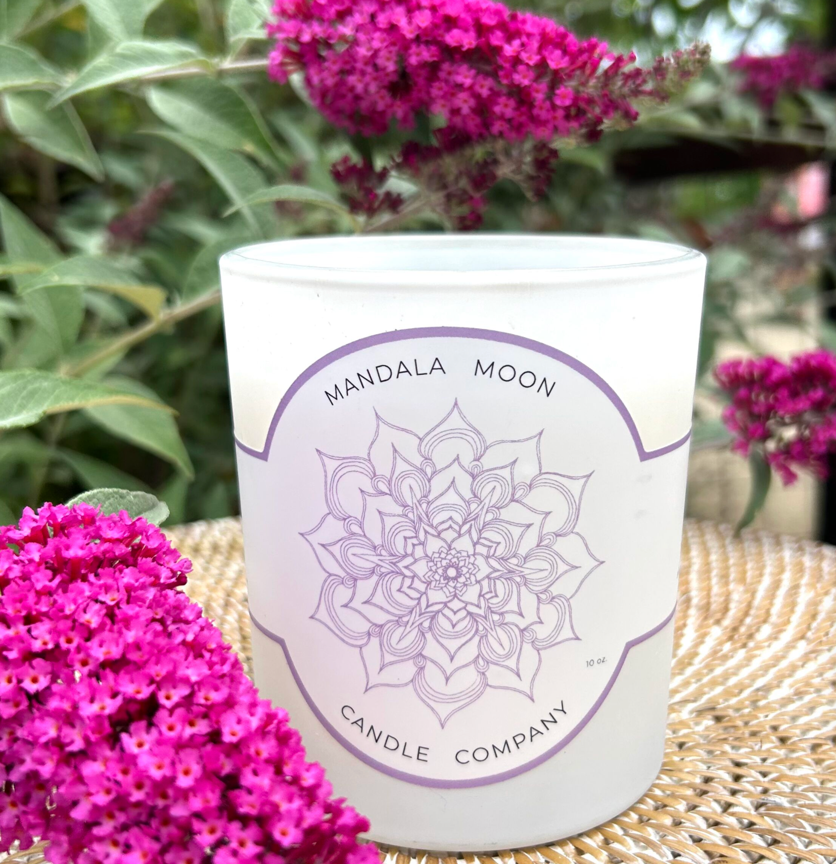 Candle with Mandala Moon Candle Company label surrounded by pink flowers