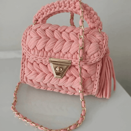 Handmade pink woven luxury handbag with gold chain strap and tassels, perfect for various outfits.